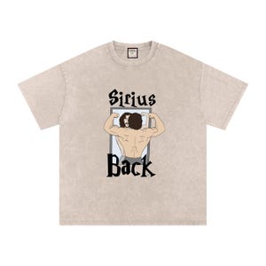 Peut inclure: T-shirt beige avec l'inscription "Sirius Back" en noir, représentant une illustration d'une personne se musclant devant un miroir. Le t-shirt a un col rond et des manches courtes. Le motif est centré sur le devant.