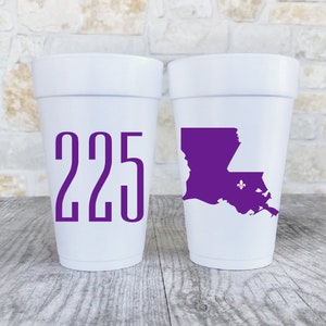 May include: Two white foam cups. The left cup features the purple text 225. The right cup displays a purple silhouette of the state of Louisiana with a small purple fleur-de-lis symbol positioned within the state outline on the cup surface.