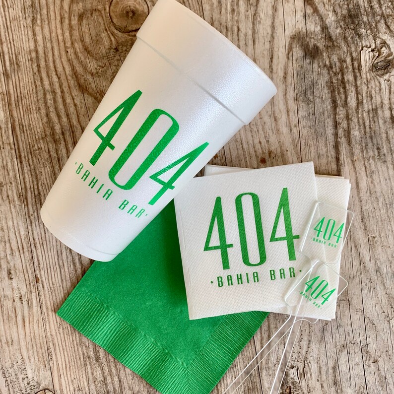 May include: A white foam cup, a stack of white paper napkins, a single green paper napkin, and two clear plastic stirrers. The cup, napkins, and stirrers all feature the green printed text 404 BAHIA BAR in a clean, sans-serif font style.