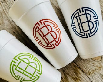 May include: Three white foam cups with a monogram design in red, blue, and green. Each cup features a circular design with the intertwined letters "EB". The cups are arranged on a rustic wooden surface.