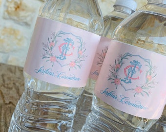 May include: Three clear plastic water bottles with pink and blue labels. The labels feature a floral design with a monogram and the text "Jordan's Coronation".