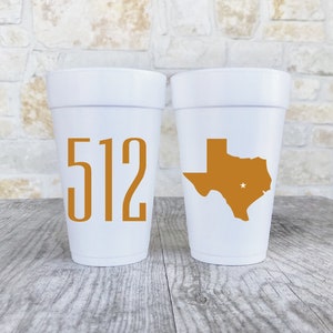 May include: Two white foam cups. One cup features the orange numbers 512 printed on the front. The other cup displays an orange silhouette of the state of Texas with a small white star marking a location within the state boundaries.