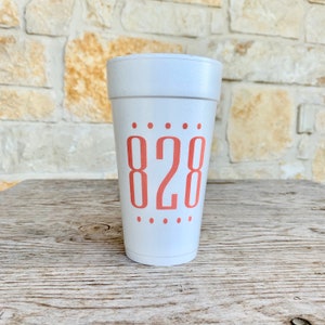 May include: A white foam cup featuring the number 828 printed in a coral-colored sans-serif font on the front. The number is centered between two horizontal rows of five small coral-colored dots, with one row above and one row below the text.