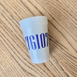 May include: A white foam cup featuring the blue printed numbers 76107 on the front. The cup has a textured surface and a wide rim, with a tapered body that narrows toward the base. The design is simple and functional, displaying the digits clearly.