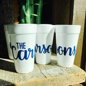 May include: Three white foam cups featuring the blue text "THE CARSONS" printed in a cursive script font. The cups are arranged in a row, displaying the personalized name across the front surface of each individual white polystyrene container.