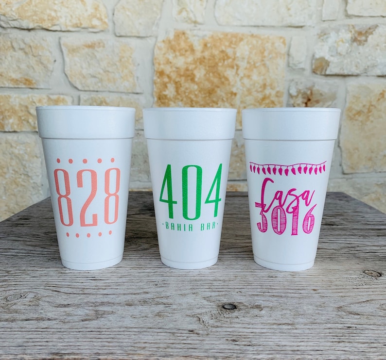 May include: Three white foam cups with custom text. The left cup features the number 828 in coral. The center cup displays 404 BAHIA BAR in green. The right cup shows a string of lights graphic above the text Casa 3016 in bright pink ink.