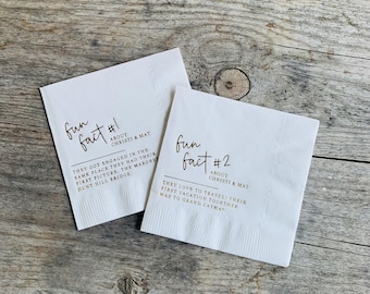 May include: Two white paper napkins with black text. One napkin reads "fun fact #1 about Christi & Mat" with a short paragraph below. The other napkin reads "fun fact #2 about Christi & Mat" with a short paragraph below.