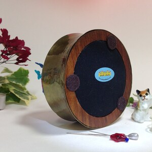 May include: A brass and wood base with a felt bottom and a sticker that reads "Wonderland in Jars". The base is decorated with colorful butterflies.