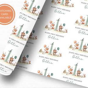 May include: White wrapping paper with a repeating pattern of a fox, bear, and number one with the text "Happy First Birthday Ollie" in a handwritten font.