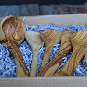 Puede incluir: Un juego de cinco utensilios de cocina de madera de olivo en una caja de cart&oacute;n con papel de seda azul. El juego incluye un cuchar&oacute;n grande, dos cucharones m&aacute;s peque&ntilde;os y dos cucharas. Tambi&eacute;n se incluye un peque&ntilde;o bote de acondicionador para madera.
