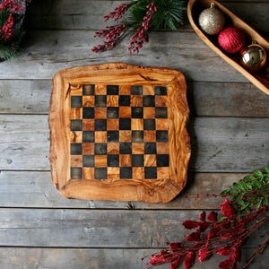 Peut inclure: Un échiquier en bois avec des cases noires et brunes, fabriqué à partir d'une dalle de bois d'olivier naturel. Le plateau a un aspect rustique et organique et est parfait pour une partie d'échecs.