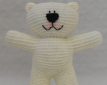 May include: A white knitted teddy bear with black eyes and pink cheeks. The bear has a simple design and is made of soft yarn.