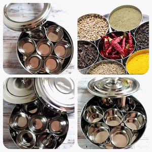 May include: A circular stainless steel spice container with a clear lid, featuring multiple small compartments. The container is filled with a variety of spices, such as red chillies, coriander seeds, and turmeric powder. The design is practical for storing and organizing spices.
