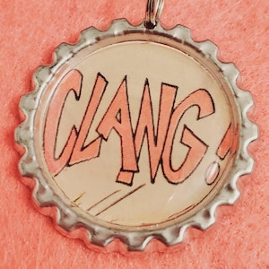 May include: A silver bottle cap with a pink and black comic book style "CLAWG!" graphic.