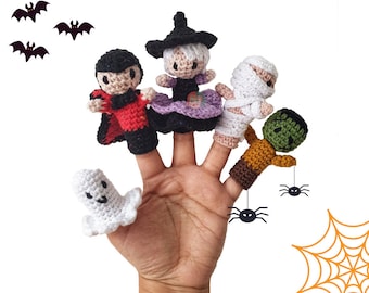 Könnte beinhalten: Satz mit sechs Fingerpuppen mit Halloween-Charakteren: eine Hexe, ein Vampir, eine Mumie, ein Frankenstein, ein Geist und eine Spinne. Die Puppen sind in verschiedenen Farben gehäkelt, darunter Lila, Rot, Weiß, Grün und Orange.