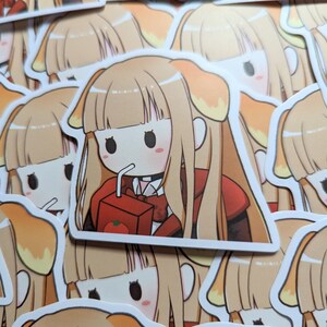 May include: A sticker featuring a cartoon illustration of a girl with long blonde hair, wearing a red and black outfit, drinking from a box of juice. The girl has a cute, anime-style appearance.