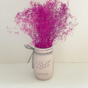 May include: A pink mason jar with the text "Ball Mason" on the front, filled with a bouquet of pink dried flowers.