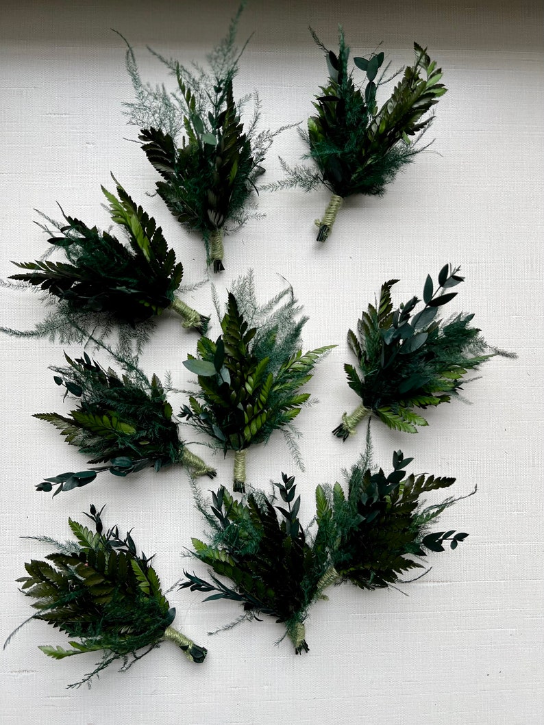 May include: Eight small bouquets of green foliage, tied with twine, arranged on a white surface.