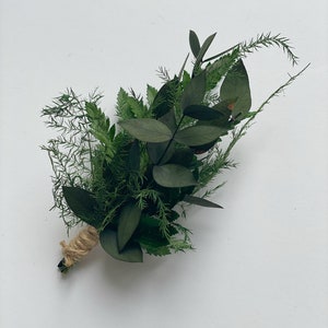 May include: A small bouquet of green foliage tied with twine. The bouquet includes eucalyptus, ferns, and other greenery.