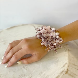 May include: A pink and brown floral wrist corsage with small pink flowers and brown stems.