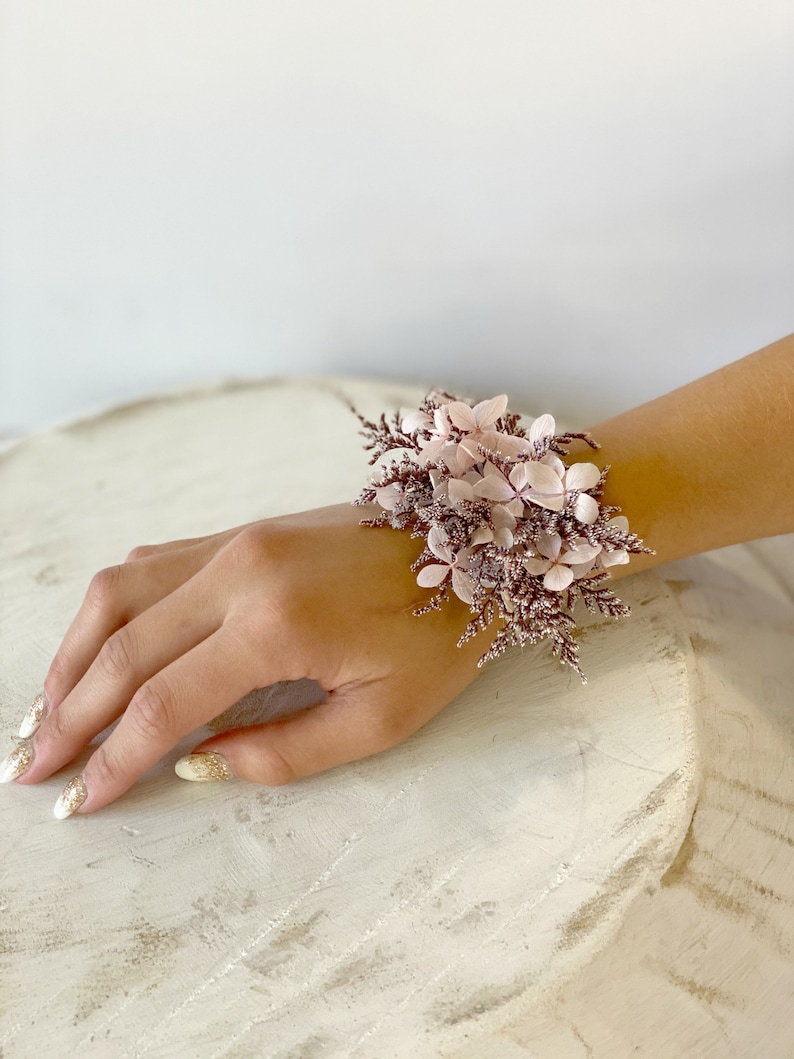 May include: A pink and brown floral wrist corsage with small pink flowers and brown stems.
