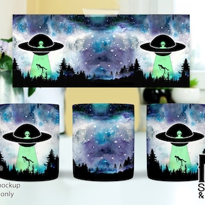 May include: Three white ceramic mugs with a watercolor design of a galaxy with stars and a green alien spaceship with a green alien inside. The spaceship is hovering over a forest with a green alien falling from the sky.