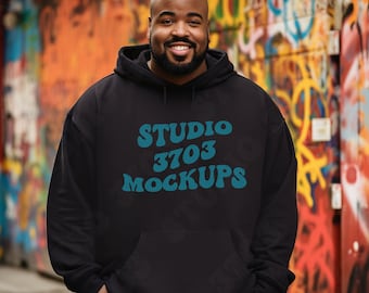 May include: A black hoodie with a blue graphic that says "Studio 3703 Mockups". The person wearing the hoodie is standing in front of a colorful graffiti wall.