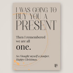 Peut inclure: Une carte de v&oelig;ux rectangulaire sur fond beige clair avec un texte brun fonc&eacute; : I WAS GOING TO BUY YOU A PRESENT. Then I remembered we are all one. So I bought myself a jumper. Happy Christmas. Un cercle dor&eacute; fin et des &eacute;claboussures de peinture dor&eacute;e sont visibles.
