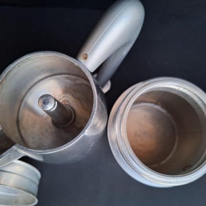 May include: Two silver metal coffee pots with a shiny finish. The pots are empty and ready to be used to brew coffee.