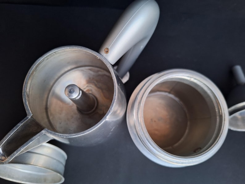 May include: Two silver metal coffee pots with a shiny finish. The pots are empty and ready to be used to brew coffee.