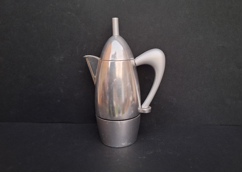 May include: A silver aluminum stovetop espresso maker with a curved handle.