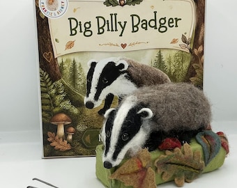 Op de afbeelding: Een naaldgevilte dasfiguur rustend op een groene viltstam versierd met stoffen bladeren, geplaatst voor een doos met het opschrift Big Billy Badger en een bosillustratie. Twee dunne metalen viltnaalden liggen op de ondergrond ernaast.