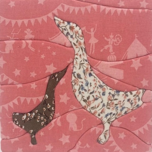 May include: A fabric wall art piece featuring two geese appliqués on a pink background. The larger goose has a cream floral pattern, while the smaller goose is dark brown with a floral print. The background fabric displays circus-themed motifs.