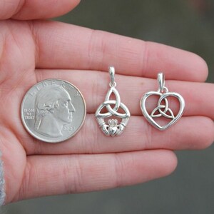 May include: Two silver Celtic knot pendants, one with a heart shape and the other with a traditional knot design, are shown next to a US quarter for size comparison.