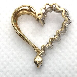 May include: A gold heart-shaped pendant with a diamond-encrusted border. The pendant is made of 14k gold and features a polished finish.