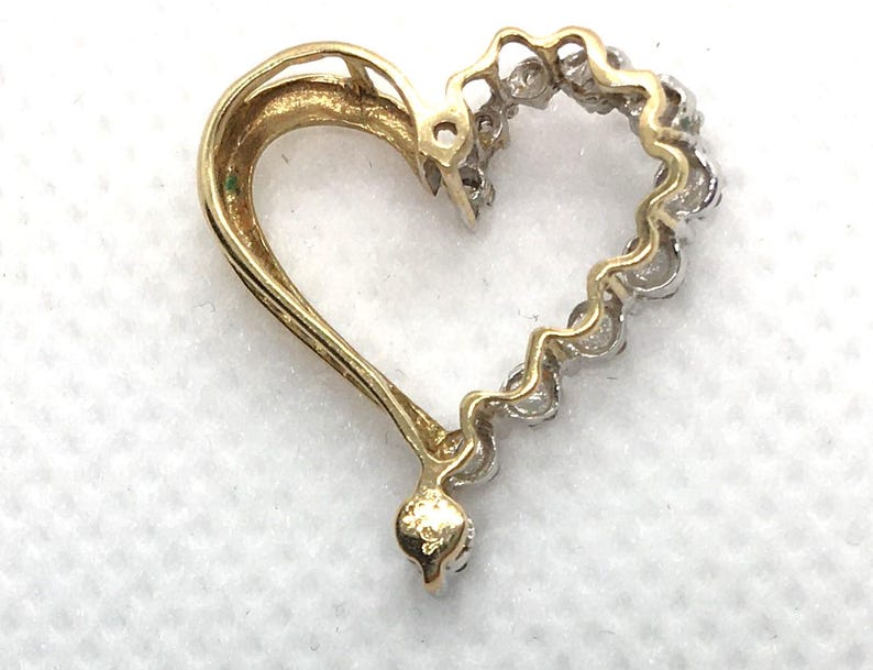 May include: A gold heart-shaped pendant with a diamond-encrusted border. The pendant is made of 14k gold and features a polished finish.