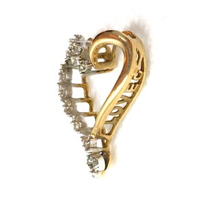 May include: Gold heart-shaped pendant with a diamond-encrusted border and the word "LOVE" inscribed on the side.