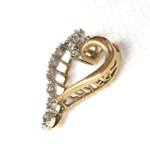 May include: A gold heart-shaped pendant with a diamond-encrusted border. The pendant has the word "LOVE" inscribed on the back.