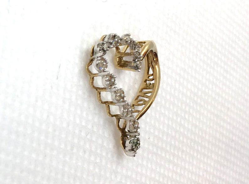 May include: A gold heart-shaped pendant with a diamond-encrusted design. The pendant features the word "LOVE" inscribed on the side.