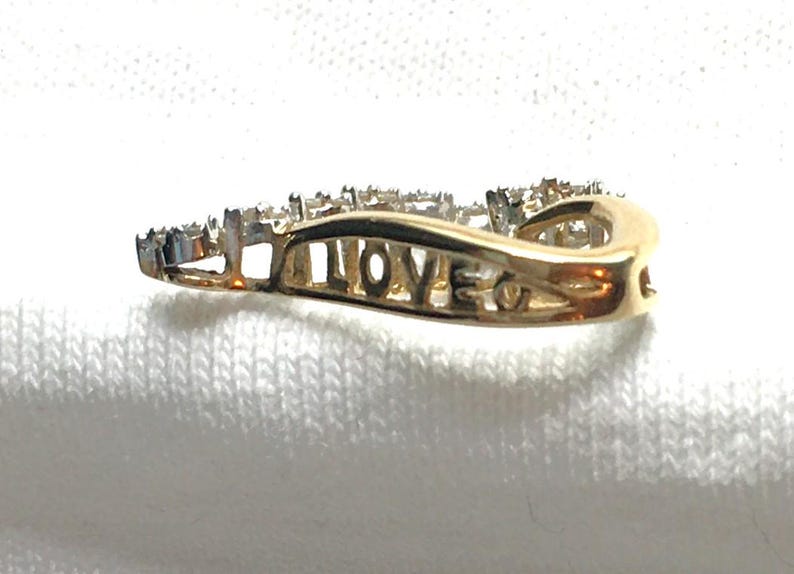 May include: A gold ring with a wave design and small diamonds set in the band. The word "LOVE" is engraved on the inside of the ring.