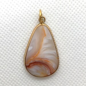 Peut inclure: Un pendentif en forme de larme avec un sertissage dor&eacute; et une pierre d'agate blanche et brune.