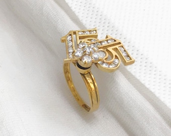 May include: A gold ring with a diamond-encrusted design featuring the number "15".