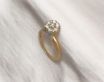 May include: A gold ring with a cluster of small diamonds set in the center.