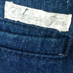 Pu&ograve; includere: Un primo piano di un tessuto denim blu con un'etichetta bianca che dice "Handmade" in corsivo.