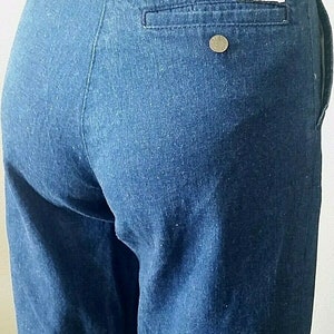 Pu&ograve; includere: Un paio di pantaloni di jeans blu scuro con una sola tasca posteriore e un piccolo bottone di metallo sulla tasca posteriore destra.