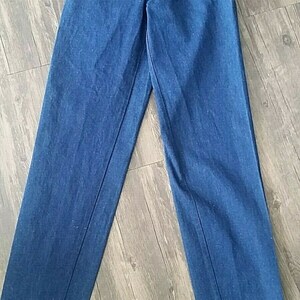 Pu&ograve; includere: Un paio di jeans blu scuro a gamba dritta con chiusura a bottone.