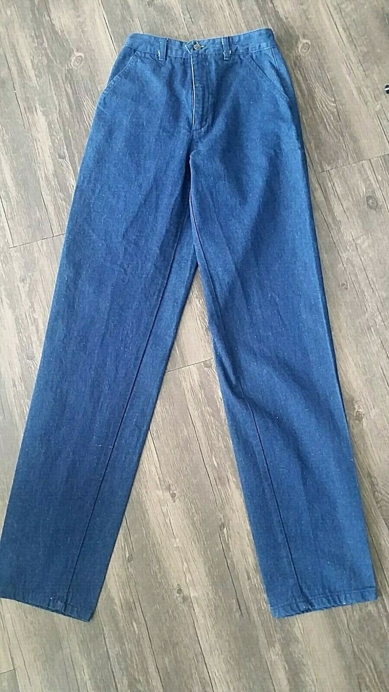 Pu&ograve; includere: Un paio di jeans blu scuro a gamba dritta con chiusura a bottone.