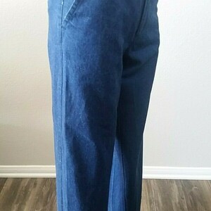 Pu&ograve; includere: Un paio di jeans in denim blu scuro con gamba dritta. I jeans hanno un design classico a cinque tasche e una chiusura a zip.