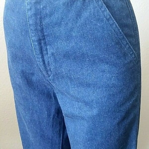 Pu&ograve; includere: Un paio di jeans blu denim con chiusura a bottone e una sola tasca posteriore.