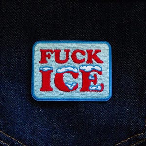 Puede incluir: Parche bordado rectangular con las palabras "FUCK ICE" en letras mayúsculas rojas sobre un fondo azul claro. La palabra "ICE" tiene un diseño de nube encima. El parche tiene un borde azul y está sobre un fondo de mezclilla azul oscuro.